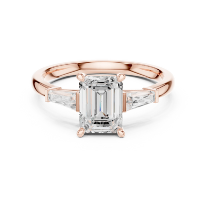 Rose gold emerald three-stone ring with tapered baguette side stones