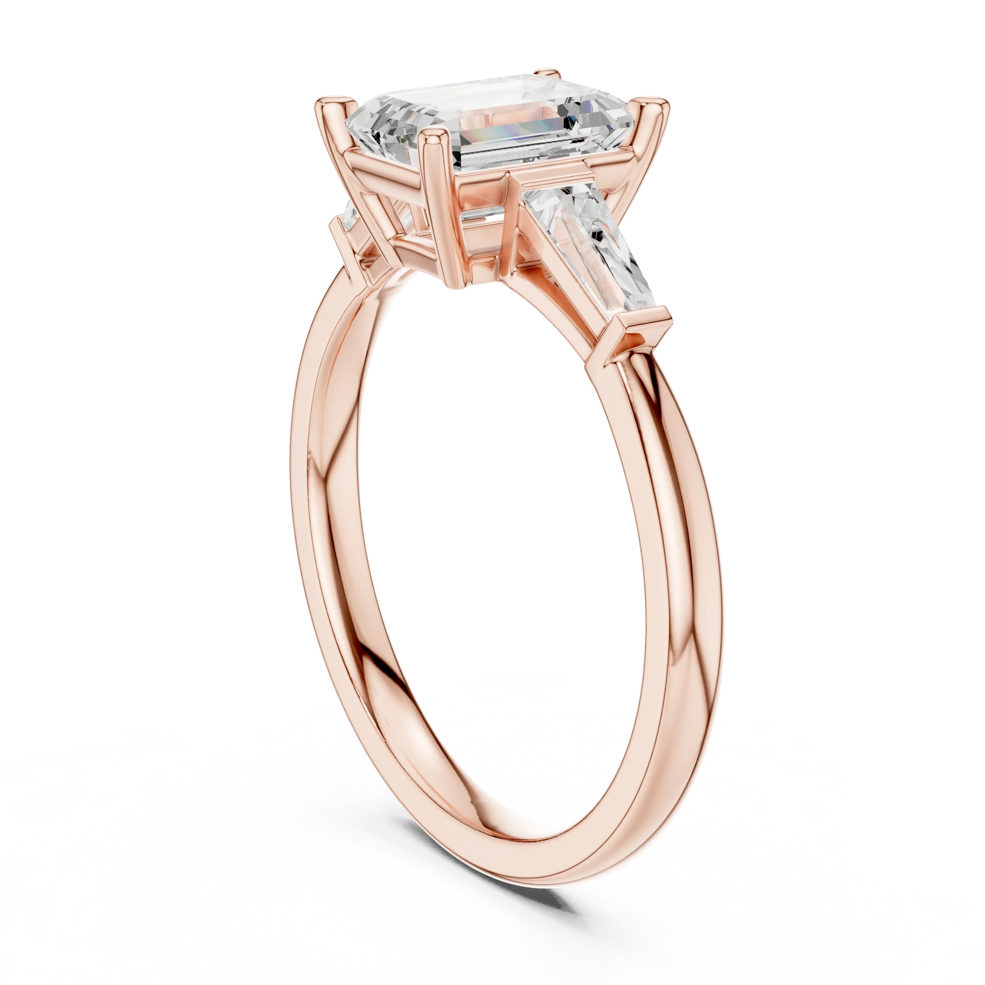 Rose gold emerald three-stone ring with tapered baguette side stones back view