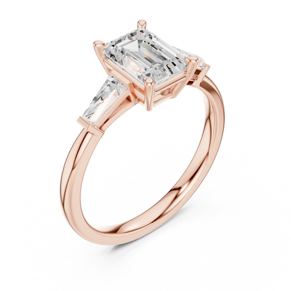 Rose gold emerald three-stone ring with tapered baguette side stones front view