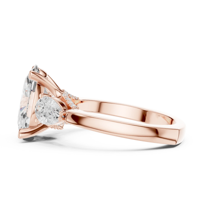 Side view of rose gold oval three stone ring highlighting pear side stones and diamond setting