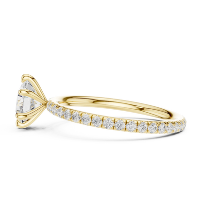 Side view of yellow gold round cut solitaire ring with thin pavé diamond band and prong setting